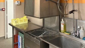 Eine gewerbliche Küche mit Edelstahlgeräten, einer Spüle und Lagerboxen.