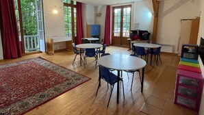 Ein geräumiges Zimmer mit Holzböden, einem großen Teppich und mehreren Tischen und Stühlen.