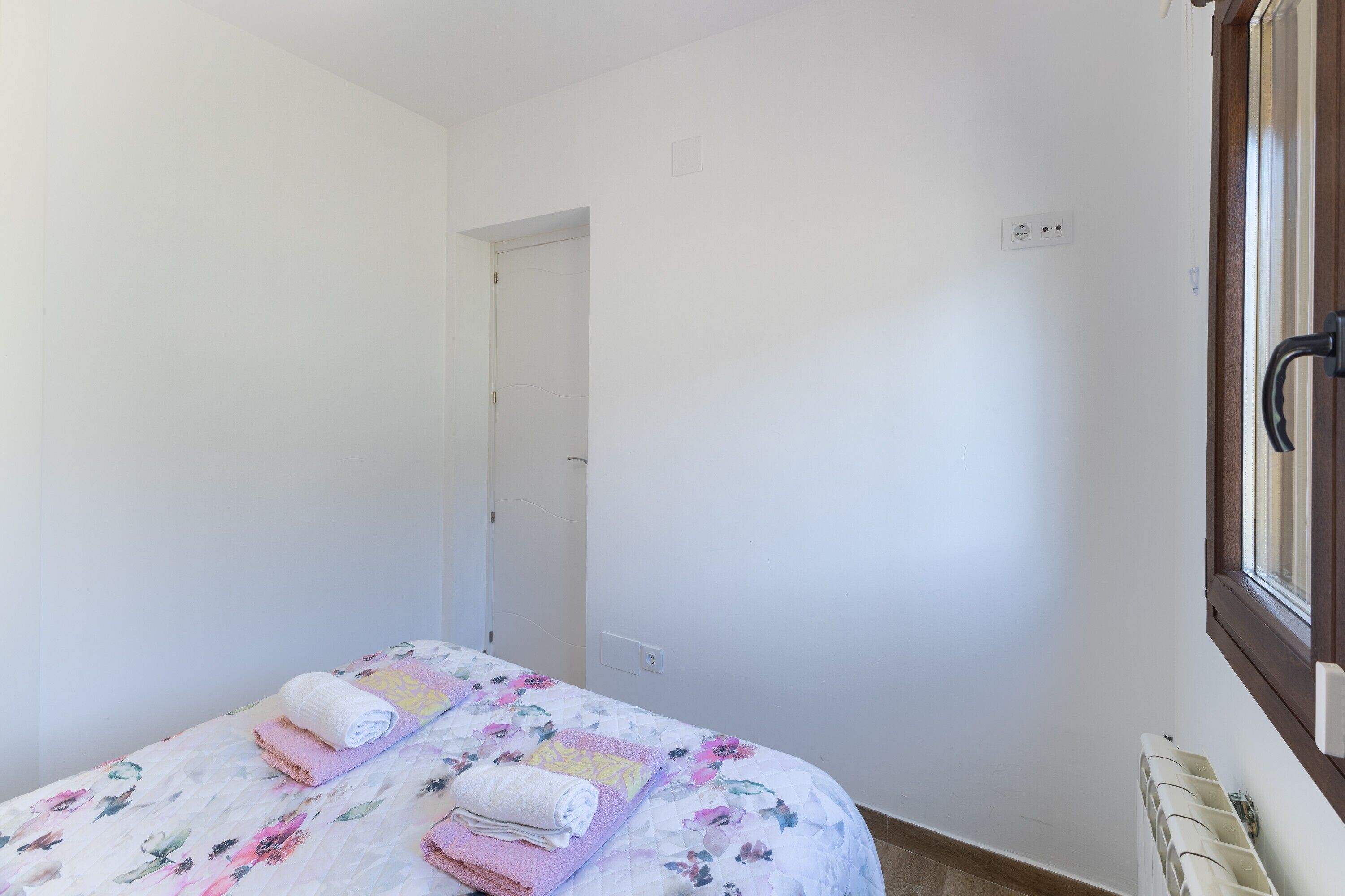A bedroom with two beds, a window, and a radiator.