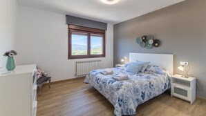 A bedroom with a bed, bedside tables, a radiator, a window, and a view of the outdoors.