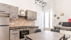 A modern kitchen with a dining area, featuring a built-in oven, a gas stove, and a large table. - La Capinera by Wonderful Italy (Noto)