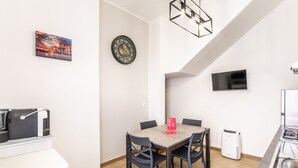 A modern kitchen with a built-in oven, a coffee machine, and a dining area with a table and chairs. - La Capinera by Wonderful Italy (Noto)
