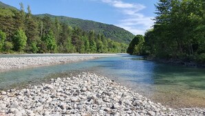 Un río de aguas transparentes, rodeado de terreno rocoso y un bosque denso.