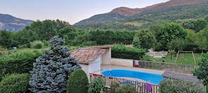 A residential area with a swimming pool, a fenced yard, and a view of mountains. - Holiday Home 'Gîte Le Devant De La Chaux' with Shared Pool, Private Terrace and Wi-Fi (Pontaix)