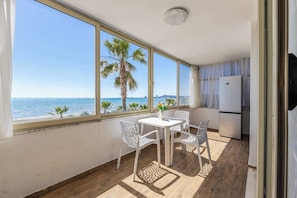 Ein Balkon mit Meerblick, einem Tisch mit Stühlen und einem Kühlschrank.
