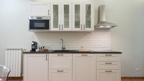 Cozinha com armários brancos, micro-ondas, fogão e pia.