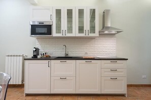 A kitchen with white cabinets, a microwave, a stove, and a sink. - CHEZ MONTI - IN HEART OF ROME (Roma)