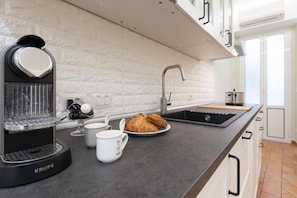 A modern kitchen with a built-in espresso machine, a sink, and a breakfast setup including croissants and coffee cups. - CHEZ MONTI - IN HEART OF ROME (Roma)