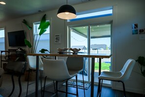 Een moderne keuken met een houten aanrecht, witte stoelen en een groot raam.