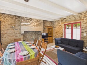 Ein Essbereich mit Steinwand, Kamin, Fernseher und einer Couch.