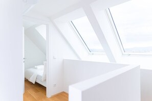 Ein modernes, weißes Interieur mit Oberlichtern, einem Bett und Blick zum Himmel.