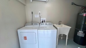 Een wasserette met twee witte wasmachines en een klein wasbakje.