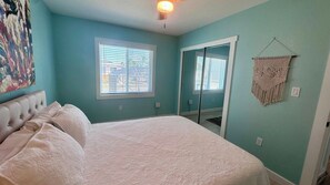 A bedroom with a bed, a window, a door, and a wall-mounted macrame decoration. - Chill Vibes B - 2 min to Beach (Fort Myers Beach)