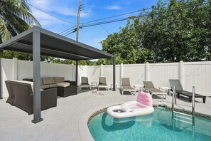 A backyard with a covered seating area, a pool, and lounge chairs. - West Palm Beach 3BR Luxury Home Near Beach&Dining (West Palm Beach)