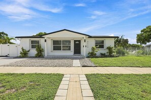 A single-story house with a front porch, a driveway, and a well-maintained lawn. - West Palm Beach 3BR Luxury Home Near Beach&Dining (West Palm Beach)