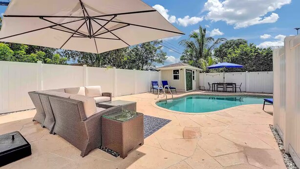 A backyard with a swimming pool, patio furniture, and a covered seating area. - West Palm Beach 3BR Luxury Home Near Beach&Dining (West Palm Beach)