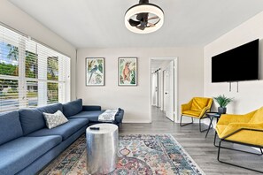 Una sala moderna con un sofá, una mesa de centro, un televisor y obras de arte en la pared.