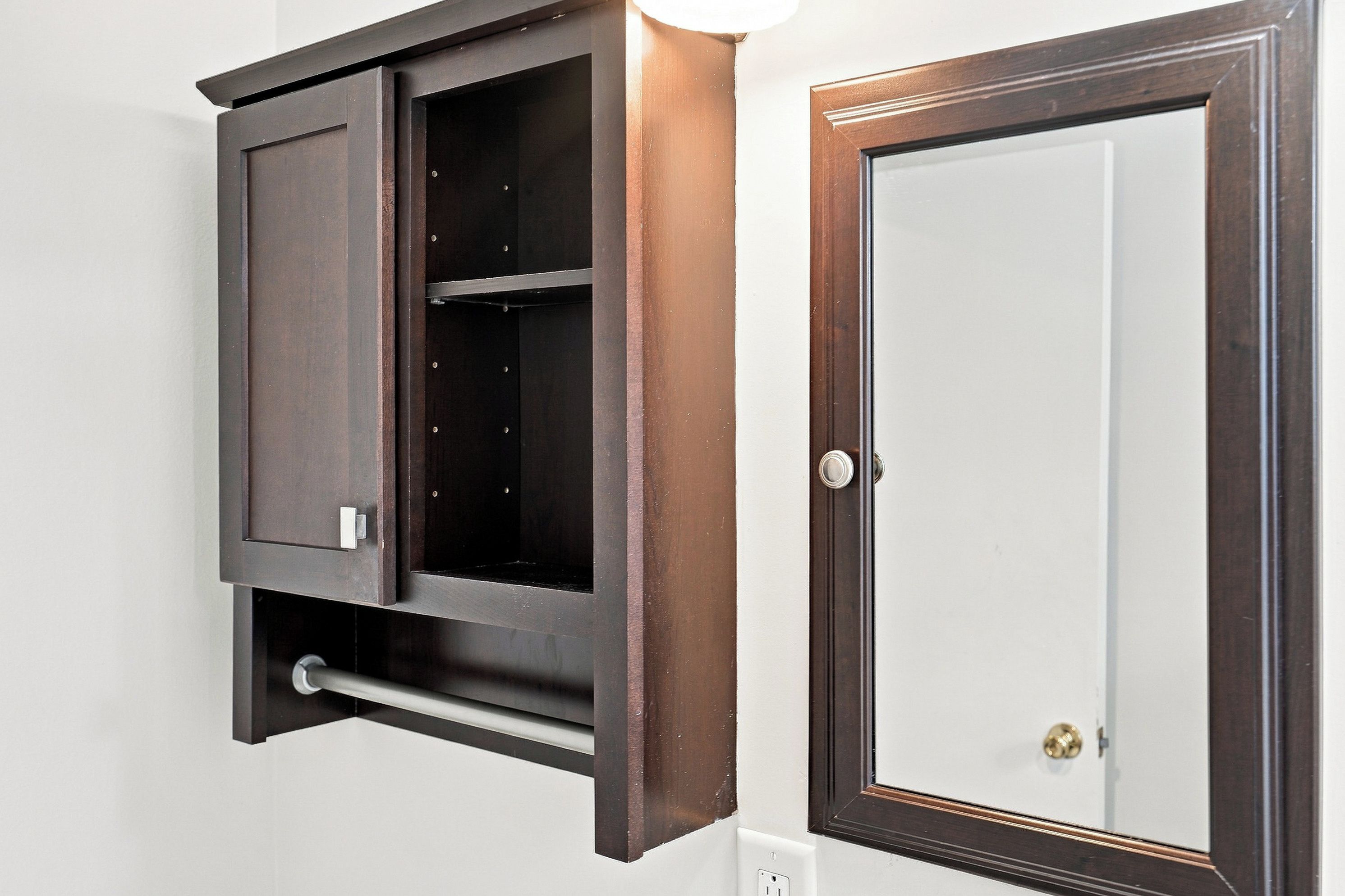 Un mueble de madera oscura con un espejo y una puerta con pomo de latón.