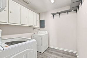 A laundry room with a washing machine, a dryer, and a cabinet above the dryer. - West Palm Beach 3BR Luxury Home Near Beach&Dining (West Palm Beach)