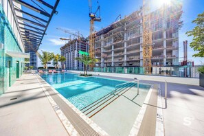 Ein Swimmingpool mit Sonnenschirm, umgeben von einem Baugebäude mit Gerüst.
