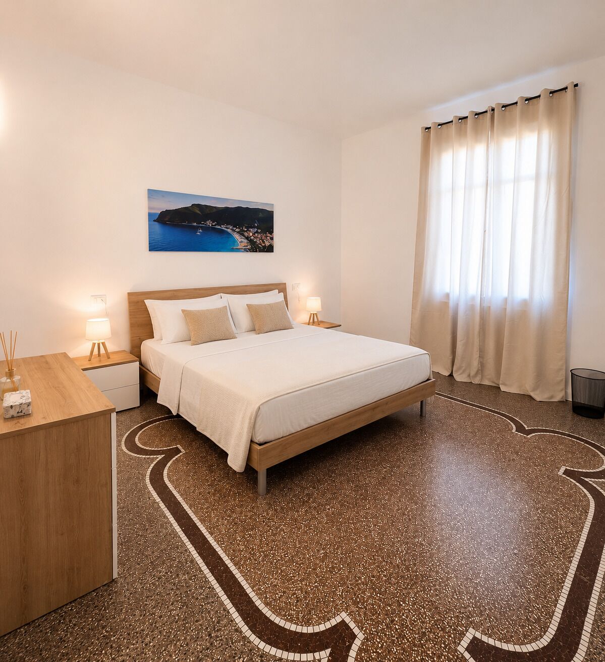 Ein Hotelzimmer mit einem Bett, Nachttischen, einem Fenster mit Vorhängen und einem Bild an der Wand.