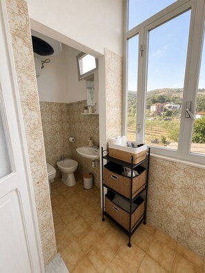 A bathroom with a toilet, bidet, sink, and a window with a view of a hilly landscape. - INDEPENDENT APARTMENT WITH PRIVATE GARDEN AND PERGOLA - DOG FRIENDLY (Valle di Vado)