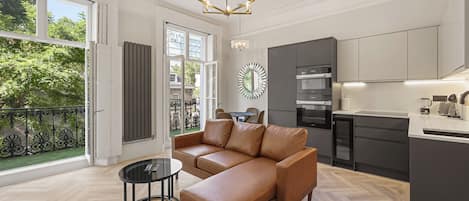 A modern kitchen with built-in appliances, a dining area with a round table, and a living room with a leather sofa and a coffee table.