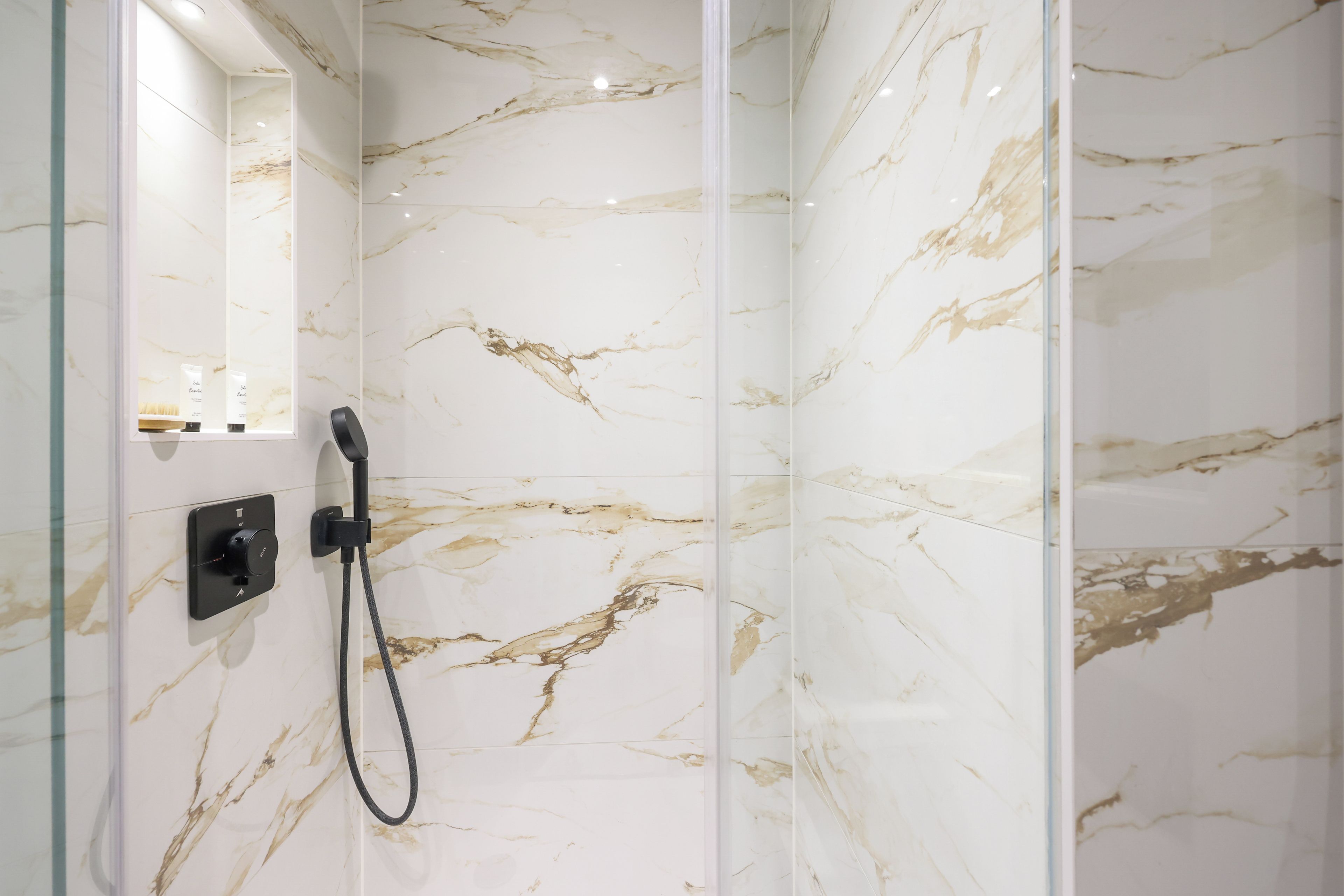 Een douche met een handdouche en bedieningspaneel.