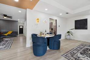 Un salon moderne comprenant un coin repas, un canapé, un ventilateur de plafond et une plante en pot.