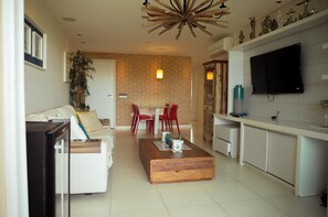 Uma sala de estar moderna com um sofá, mesa de centro, cadeiras vermelhas e uma televisão.
