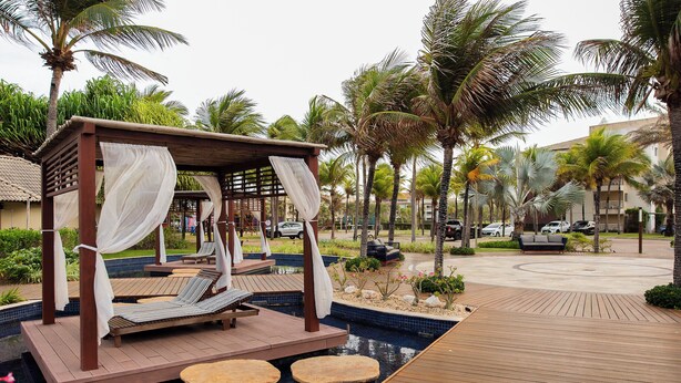 Un espace aménagé au bord de la piscine, avec une terrasse en bois, des chaises longues et un coin salon abrité.