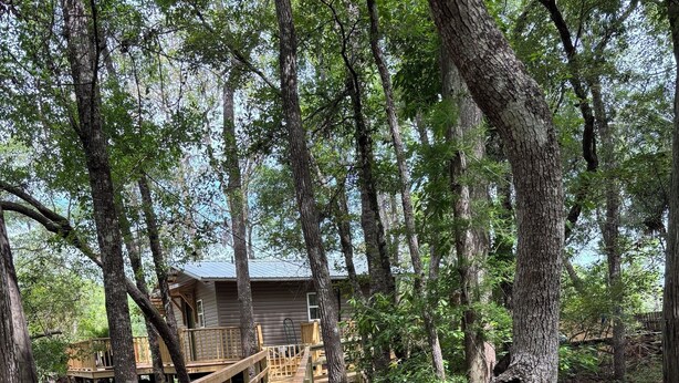 A wooden bridge leading to a cabin with a sign that reads 'Welcome to our Cabin.' - Waterfront Cabin in Hilliard, FL (Hilliard)
