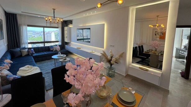 A modern living room with a sofa, coffee table, and decorative flowers. - 2-bedroom apartment in adorable Tangier with AC comfort (Tangier)