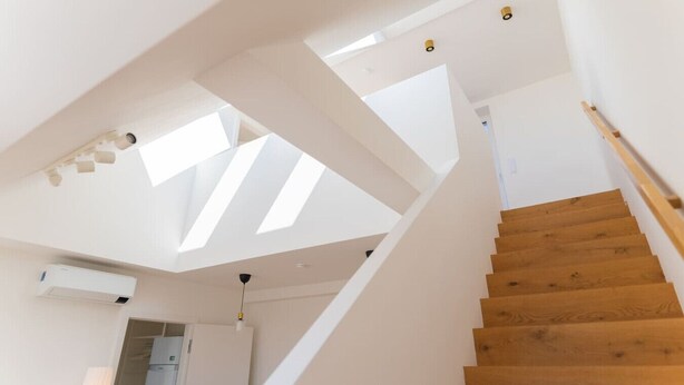 A modern staircase with wooden steps and white walls, leading to a room with skylights. - Maisonette apartment by Schönbru (Vienna)