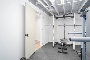 Un gimnasio con una estructura para sentadillas, banco de pesas y discos de pesas.