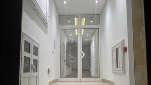 Eine Treppe führt zu einer Zwischenebene mit Glastüren, weißen Wänden und eingelassener Beleuchtung.