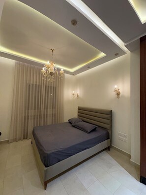 A modern bedroom with a bed, chandelier, and wall sconces. - Vauban Residence, 2 Bedroom Apartment Terrace Lake and city View (Tunis)