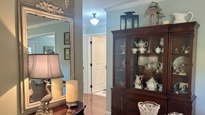 Quarto com um espelho grande, um armário com portas de vidro e uma mesa com abajur e velas.