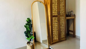 A room with a wooden wardrobe, a mirror, and a small table with items on it. - Nusa Penida Homestay (Penida Island)