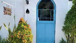 A white building with a blue door, a small window, and a sign that reads 'NOJA PENIDA HOMESTAS.' - Nusa Penida Homestay (Penida Island)