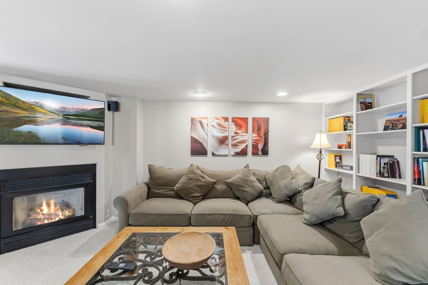 A living room with a fireplace, a sectional sofa, a coffee table, and a bookshelf.