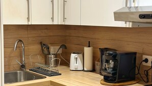 Moderni keittiö, jossa on ruostumattomasta teräksestä valmistettu pesuallas, Bosch-kahvinkeitin, leivänpaahdin ja Bosch-espressokone.