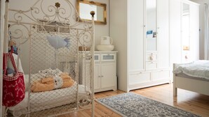 Un dormitorio con una cama con dosel, un armario blanco, un archivador pequeño y una alfombra azul estampada.