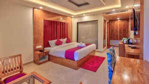 Ein modernes Hotelzimmer mit Bett, Nachttisch, Stuhl und Schreibtisch mit Sitzmöglichkeit.