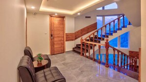 Ein modernes Interieur mit Treppe, einer Holztür und einer Sitzecke mit Tisch und Stühlen.
