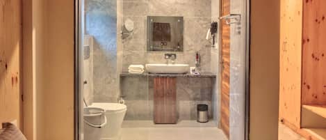 A modern bathroom with a glass door, a sink, a toilet, and a shower area.