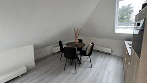 A modern kitchen with a dining area, including a round table with chairs, a window, and a built-in oven.