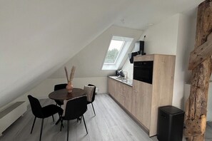 Eine moderne Küche mit Oberlicht, einem Essbereich mit Tisch und Stühlen sowie einer Wand mit Holzpaneelen.