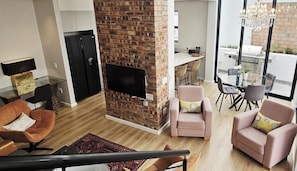 Ein modernes Wohnzimmer mit Kamin, Sitzgelegenheiten, Essbereich und Küche.