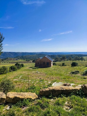 Ein Landhaus mit geneigtem Dach, umgeben von einer grünen Wiese und einem Zaun.